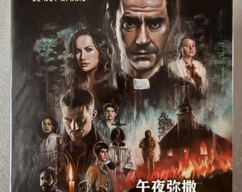 Puede incluir: Una caja de Blu-ray para la serie Midnight Mass, con un collage oscuro e ilustrado del reparto, una iglesia en llamas y el texto BE NOT AFRAID, MIDNIGHT MASS y caracteres chinos. La parte superior muestra el logo azul de Blu-ray Disc.
