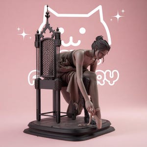 May include: A detailed figurine of a person with hair in a bun, wearing a draped garment, sitting on a tall black gothic-style chair with a lattice back. The figure is adjusting a light pink ballet slipper on one foot, set on a black base.