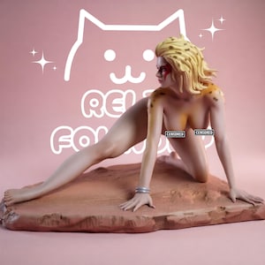 May include: A collectible figurine of a feline-inspired character with blonde hair, leopard-like spots on the shoulders and head, and red facial markings. The figure is in a crouching pose on a textured, rocky base with two silver wrist bangles.