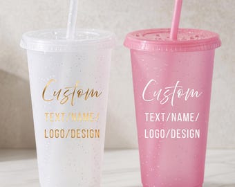 Puede incluir: Dos vasos de plástico reutilizables con tapas y pajitas. El vaso de la izquierda es blanco translúcido con texto dorado Custom TEXT/NAME/LOGO/DESIGN. El vaso de la derecha es rosa translúcido con texto blanco Custom TEXT/NAME/LOGO/DESIGN.