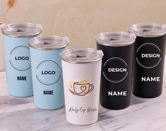 Puede incluir: Cinco vasos cilíndricos con tapas transparentes, dispuestos en grupo. Dos son azul claro con logotipos circulares y el texto "LOGO" y "NAME". Uno es blanco con un gráfico de taza de café y "Daily Cup Studio". Dos son negros con "DESIGN" y "NAME".