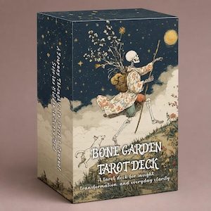 Op de afbeelding: Een rechthoekige tarotkaartendoos met de titel Bone Garden Tarot Deck. De voorkant toont een skelet in een bloemrijke mantel die met een staf loopt, een hond en een volle maan tegen een sterrenhemel. De tekst op de zijkant luidt A Journey Through Life, Death & Renewal.