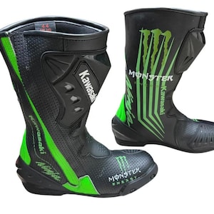 Puede incluir: Un par de botas de moto negras y verde neón con los logotipos de Kawasaki y Monster Energy. Las botas tienen secciones de cuero perforado, paneles protectores moldeados y el texto Ninja impreso en el lateral. Talla 44 visible.