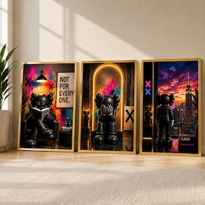 Peut inclure: Trois impressions d'art mural encadrées représentant des personnages noirs de style KAWS. Le premier montre un personnage lisant avec le texte NOT FOR EVERY ONE. Le deuxième montre un personnage assis dans une arche. Le troisième montre une ville.
