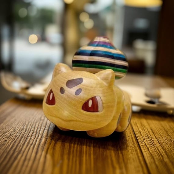 Hand-carved natural wood Bulbasaur that spins on a magnetic base — genuine woodcraft meets Pokémon nostalgia in a desk piece that doesn't look like merch.