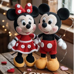 May include: Two handmade crochet dolls representing cartoon mice. The left doll wears a red dress with white polka dots and a matching bow. The right doll wears red shorts with two white buttons. Both have black ears, cream faces, and yellow shoes.