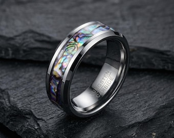 May include: A polished tungsten carbide ring featuring a central inlay of iridescent abalone shell with vibrant green, blue, and purple hues. The interior of the band is clearly engraved with the text TUNGSTEN CARBIDE.