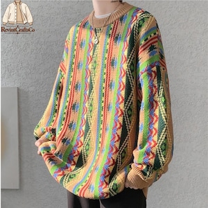 May include: A long-sleeve knit jumper featuring a tan base colour with vertical stripes in shades of green, blue, red, and yellow. The garment has a ribbed crew neckline and ribbed cuffs, showcasing a complex, repeating geometric pattern.