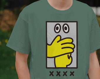 May include: A sage green t-shirt featuring a rectangular graphic print. The design shows a pair of wide eyes above a yellow hand covering a mouth, with four black 'x' symbols positioned in a horizontal row directly below the rectangular frame.