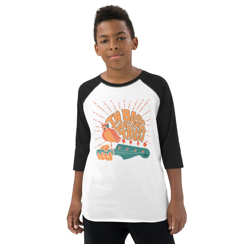 May include: A white and black baseball tee shirt with a graphic of a bass guitar and an owl with the text "In Bass We Trust".
