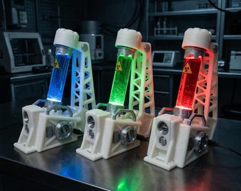 Può includere: Tre supporti da laboratorio in plastica bianca, ciascuno contenente una fiala di vetro cilindrica riempita con liquido luminoso blu, verde o rosso. Ogni fiala presenta un simbolo giallo di rischio biologico ed è sostenuta da un telaio.