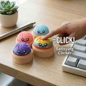 Könnte beinhalten: Vier kleine, runde, bunte Silikon-Fidget-Toys in Knödelform, die jeweils auf einer hellen, runden Basis stehen. Die Spielzeuge haben lächelnde Gesichter mit großen Augen und sind in Blau, Pink, Lila und einem Regenbogenverlauf gehalten. Der Text lautet CLICK! Satisfying Clicker.