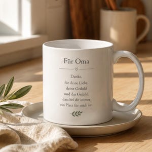 Op de afbeelding: Een witte keramische mok met de Duitse tekst 'Für Oma', gevolgd door een hartpictogram en een gedicht dat dankbaarheid uitdrukt voor liefde, geduld en geborgenheid, afgewerkt met een kleine groene bladillustratie onderaan de tekst.