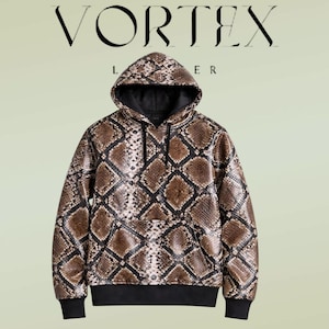Peut inclure: Un sweat à capuche à manches longues avec un motif peau de serpent marron et noir. Le vêtement comprend une capuche avec des cordons noirs, une poche kangourou avant, ainsi que des poignets et un ourlet côtelés noirs. Texte VORTEX LEATHER.
