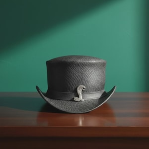 Puede incluir: Un sombrero de copa negro con una superficie texturizada similar al cuero y una cinta negra a juego. Un emblema de metal plateado con forma de serpiente cobra está centrado en la parte delantera de la cinta, añadiendo un detalle metálico.