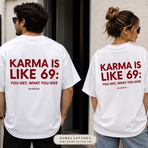 May include: A white short-sleeved t-shirt featuring dark red text on the back that reads: KARMA IS LIKE 69: YOU GET, WHAT YOU GIVE, followed by the script text AurelixFinds. The shirt has a crew neckline and a relaxed, loose-fitting silhouette.