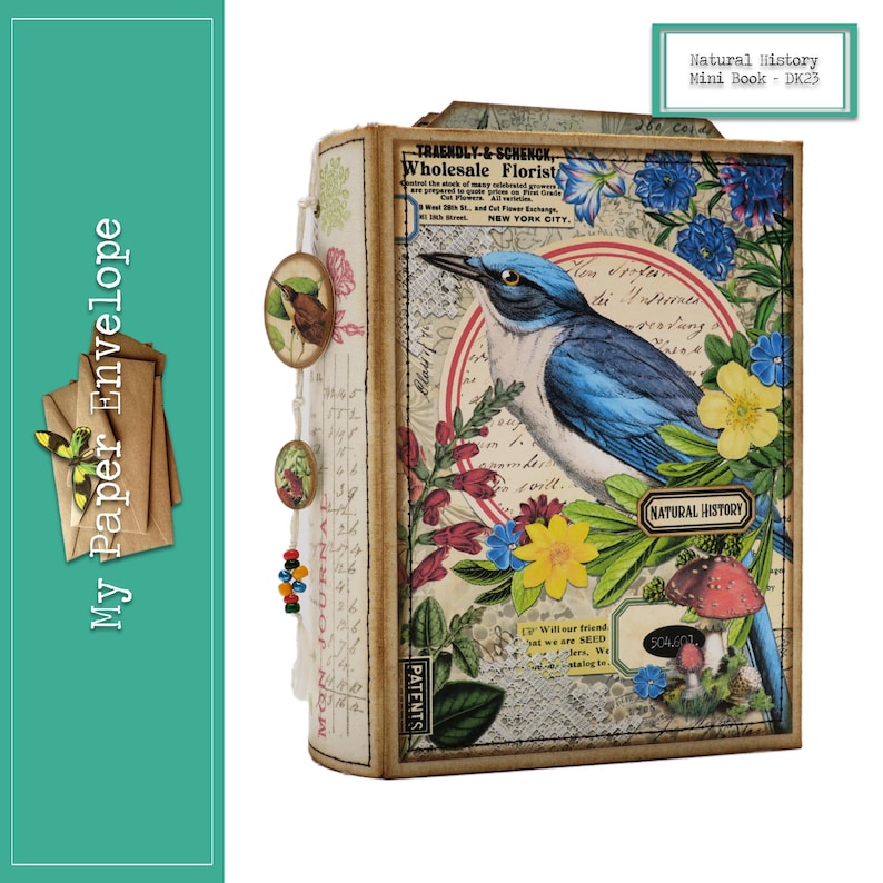 Op de afbeelding: Een mini-boek in vintage stijl met een blauwe vogel en een bloemenontwerp. De omslag heeft de tekst "Natural History" en "DK23".