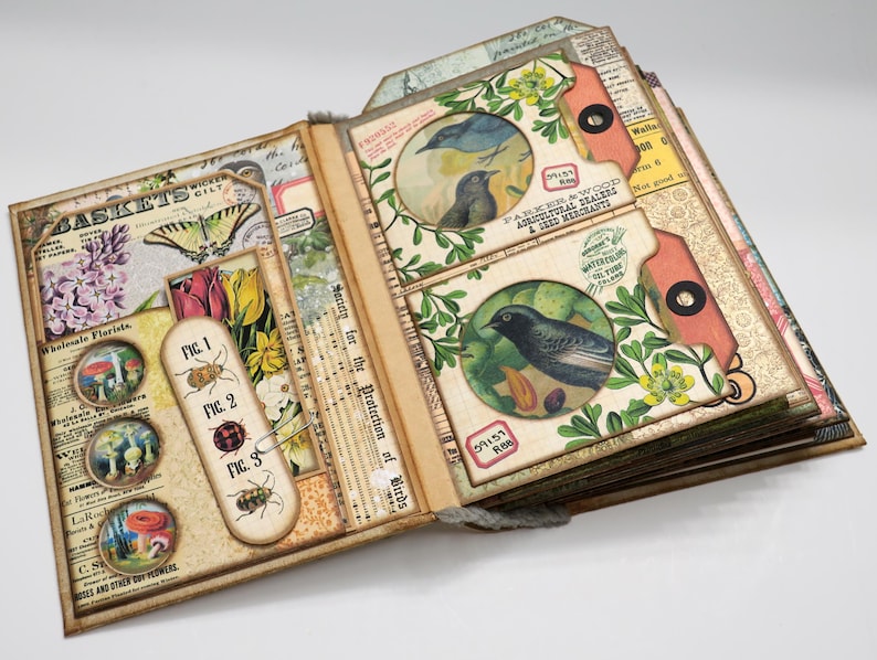 Op de afbeelding: Een open vintage scrapbook met een bruine leren omslag en pagina's versierd met bloemenpatronen, vogels en insecten. De pagina's zijn gevuld met ephemera, waaronder een label met de tekst "Vereniging ter bescherming van vogels".