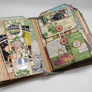 Op de afbeelding: Een vintage-stijl scrapbook met pagina's versierd met botanische illustraties, zaadzakjes en ephemera. De pagina's zijn opengeklapt om een ​​sectie met een knoop en touw te onthullen.