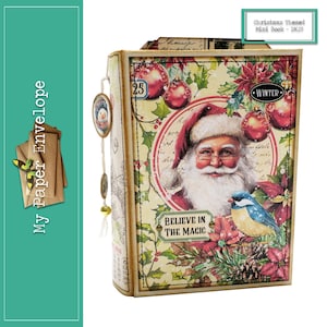 Puede incluir: Un mini libro con temática navideña con una ilustración de Papá Noel, acebo y el texto "Cree en la magia". La portada del libro está decorada con una etiqueta roja y blanca "Invierno" y una etiqueta roja y blanca "25".