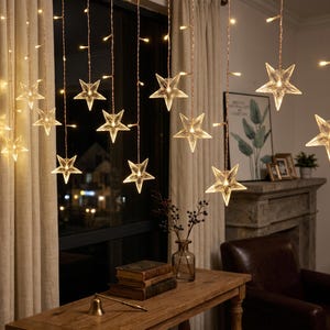 May include: A string of hanging curtain lights featuring multiple clear, five-pointed star-shaped ornaments. Each star contains a warm white LED light, suspended from thin copper-colored wires that create a cascading, vertical illumination effect.