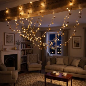 May include: A string of warm white LED fairy lights featuring small metallic star-shaped ornaments. The lights are draped in multiple loops across a wooden ceiling beam, creating a glowing decorative display that illuminates the room.