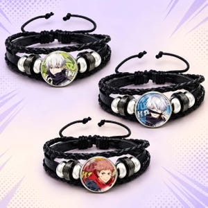 Puede incluir: Tres pulseras de cuero trenzado negro con cabujones de vidrio circulares. Dos pulseras muestran un personaje de anime con cabello blanco, sobre fondos verde y azul. La tercera pulsera presenta un personaje con cabello rosado.