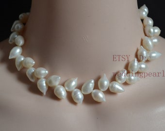 May include: A white pearl necklace with a teardrop shape. The pearls are strung on a thin wire and are arranged in a cascading pattern. The necklace is approximately 16 inches long.