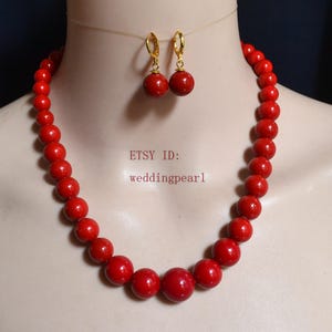 May include: A red beaded necklace and matching earrings set. The necklace features large, round beads, and the earrings have a similar design. The jewelry is displayed on a mannequin. The text "ETSY ID: weddingpearl" is visible.