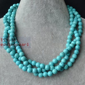 Può includere: Una collana di colore turchese blu fatta di perline rotonde. La collana è composta da tre file di perline.