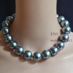 Puede incluir: Un collar de una sola hebra con perlas grandes, redondas y de color gris metálico con un acabado brillante. El texto "ETSY ID: weddingpearl" es visible en rojo en el lado derecho de la imagen, posicionado cerca de las perlas en el cuello.