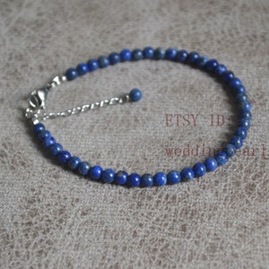 May include: A delicate blue lapis lazuli beaded bracelet with a silver adjustable clasp. The bracelet is approximately 7 inches long and features small, round beads.
