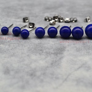 May include: A set of 8 pairs of blue lapis lazuli stud earrings in various sizes. The earrings are made of stainless steel and have a polished finish.