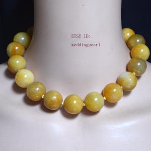 May include: A necklace of large, round, yellow beads. The beads have a marbled appearance with shades of yellow and brown. The necklace is strung on a thin, light-colored cord. The text "ETSY ID: weddingpearl1" is visible.