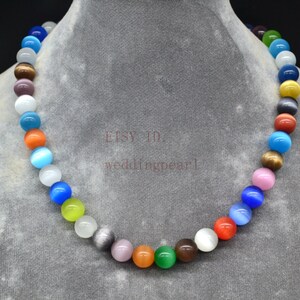 Può includere: Una collana colorata realizzata con perline rotonde in vetro iridescente. Le perline sono infilate su un filo trasparente e sono disposte a forma di arcobaleno. La collana è lunga circa 45 cm.