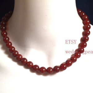 May include: A red carnelian bead necklace. The necklace is made of round beads and is approximately 18 inches long.