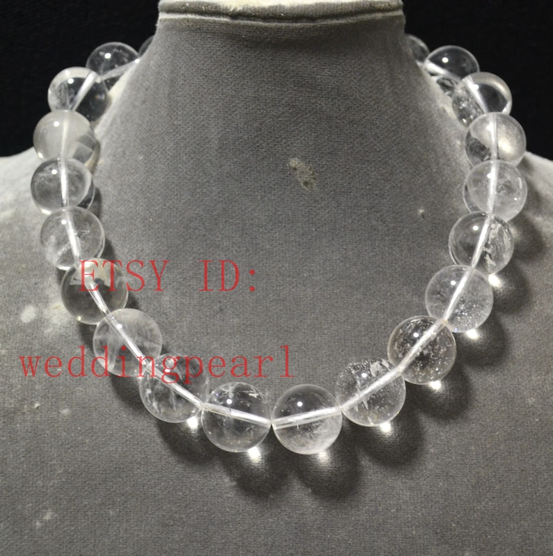 May include: A clear crystal bead necklace with a white string. The beads are round and have a smooth, polished finish. The necklace is displayed on a mannequin's neck. The text "ETSY ID: weddingpearl" is visible in the image.