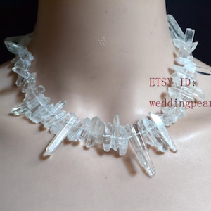 May include: A clear quartz crystal necklace. The necklace is made up of multiple clear quartz crystal points of varying lengths. The crystals are strung together to form a collar. The Etsy ID is weddingpearl1.