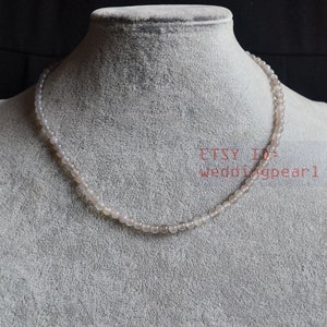 May include: A subtle necklace featuring small, spherical, pale beads. The necklace is presented on a grey mannequin, highlighting its understated charm. The text "ETSY ID: weddingpearl" is visible.
