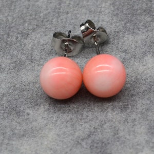 May include: A pair of pink coral stud earrings with silver posts.