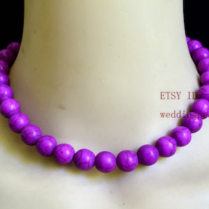 May include: A purple necklace made of round beads. The beads have a marbled pattern.