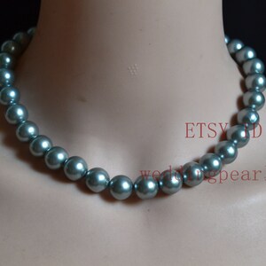 May include: A gray pearl necklace with a silver sheen. The necklace is made of large, round pearls and is approximately 18 inches long.