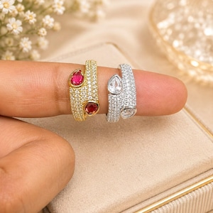 Anello di fidanzamento con rubino sintetico, taglio a pera con alone in stile Art Déco, fascia in oro e argento.