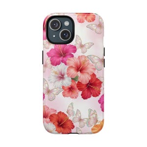 Peut inclure: Une coque de smartphone avec un fond rose clair orné d'un motif de fleurs d'hibiscus vibrantes dans des tons de rouge, rose et blanc, entremêlées de papillons délicats et translucides aux détails d'ailes aux reflets irisés.