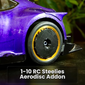 May include: A purple remote-controlled car featuring a black wheel with a gold rim and a black circular aerodisc cover. The text 1-10 RC Steelies Aerodisc Addon is displayed at the bottom of the image, highlighting the wheel modification component.