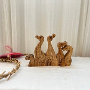 May include: Wooden puzzle of four ducks, each with a different pose, interlocking to form a group. The ducks are a dark brown colour and have a natural wood finish.