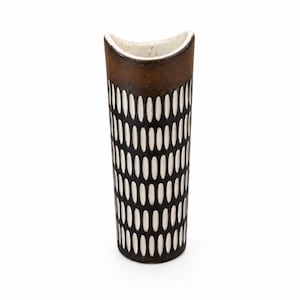 Pode incluir: Um vaso cilíndrico de cerâmica com um esmalte castanho escuro na borda superior e um padrão repetitivo de formas ovais brancas verticais sobre um fundo castanho escuro que cobre o corpo. O vaso tem uma abertura superior curva em meia-lua.