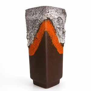 May include: A tall, square-shaped ceramic vase with a dark brown matte base. The upper section features a textured, lava-like glaze in vibrant orange, transitioning into a rough, cratered white and grey finish at the top rim of the vessel.