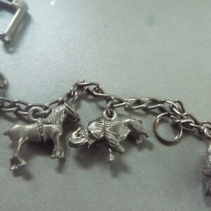 May include: A silver charm bracelet with animal charms, including a horse, elephant, and bird. The bracelet is made of a silver chain with a lobster clasp.