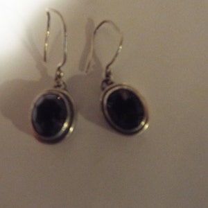 May include: A pair of silver earrings with oval-shaped black gemstones.